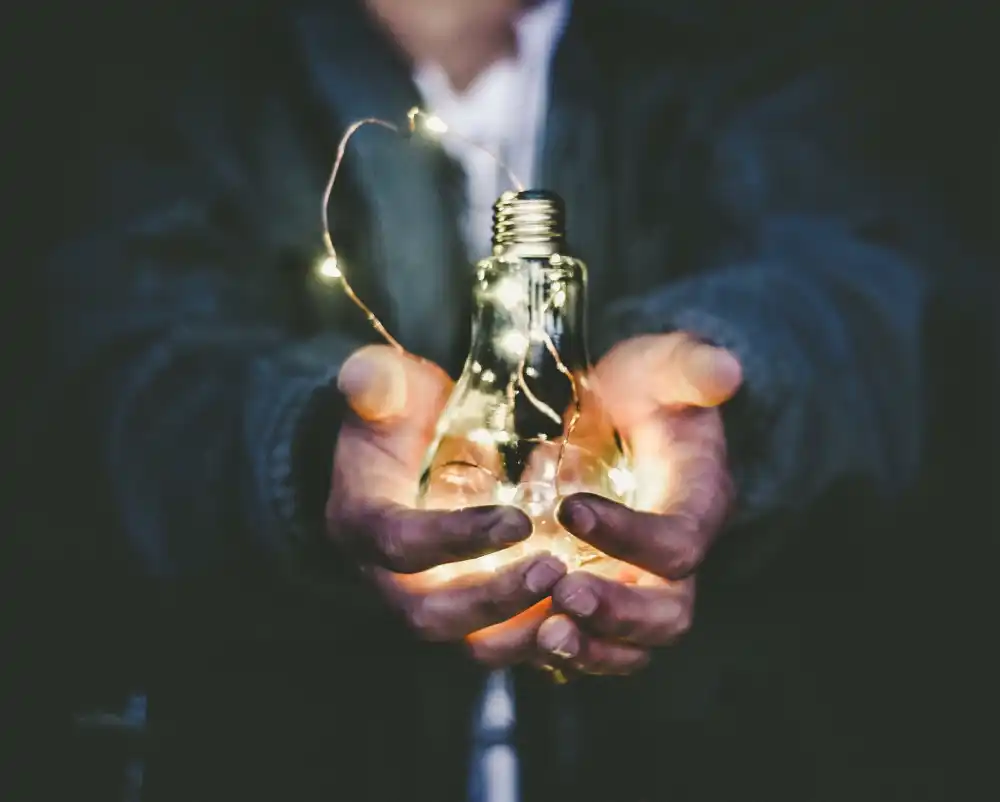 A man holding a lightbulb in his hands, this is a metaphor for the light bulb moment when our services work for you.