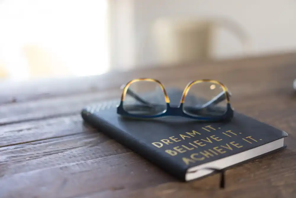 A book with glasses on top. This is a motivational metaphor of a life coaching transformation with Fatima Sabeur.